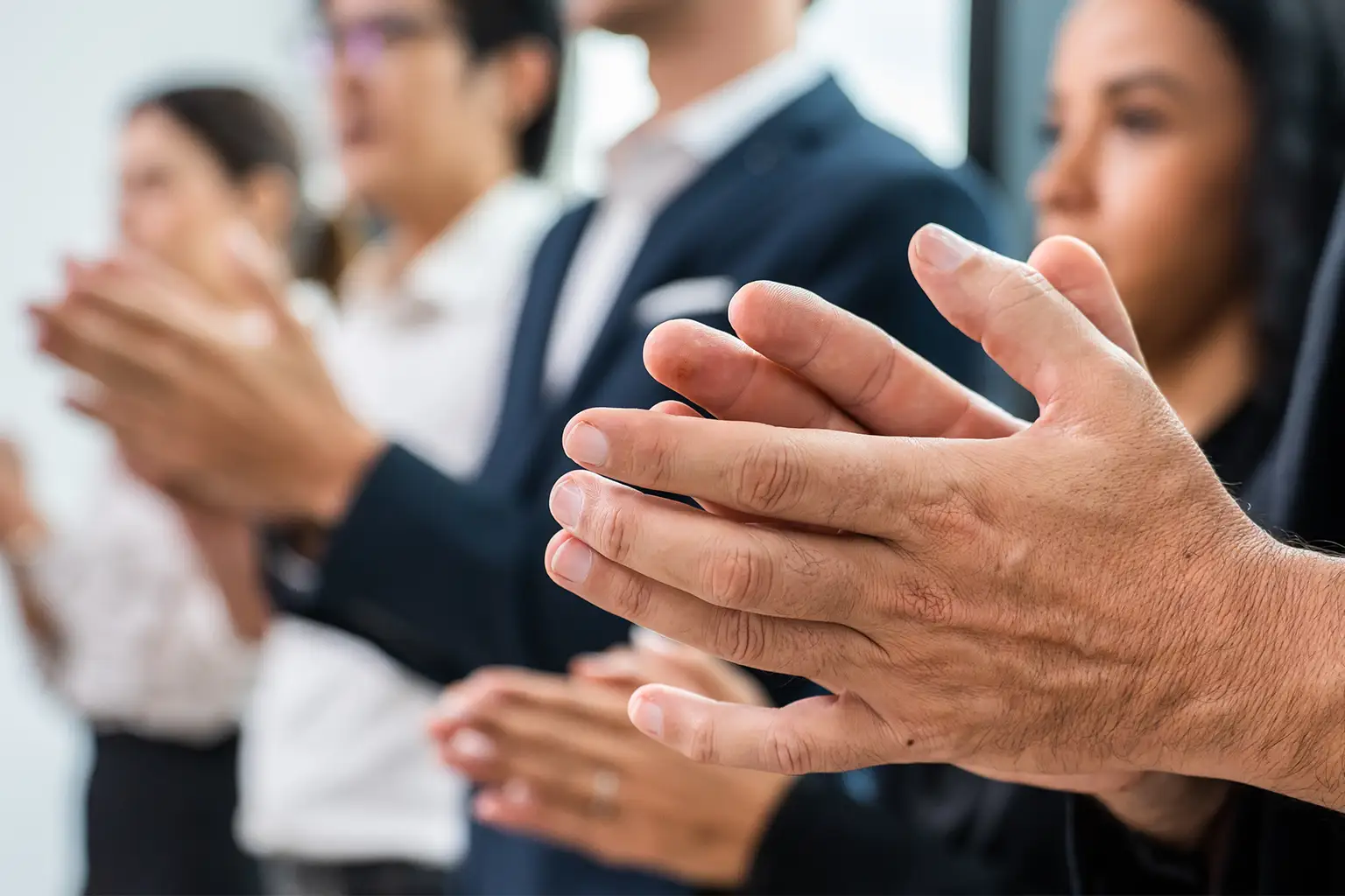 Business people clap in a crowd.